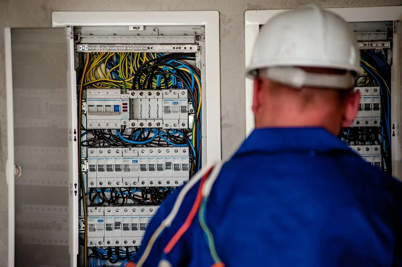 Elektriker mit Schutzhelm vor einem geöffneten Stromverteiler